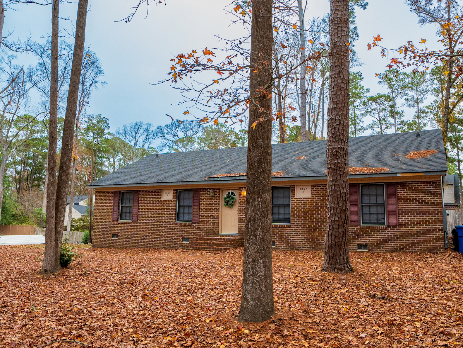 Brick ranch front with fall leaves.