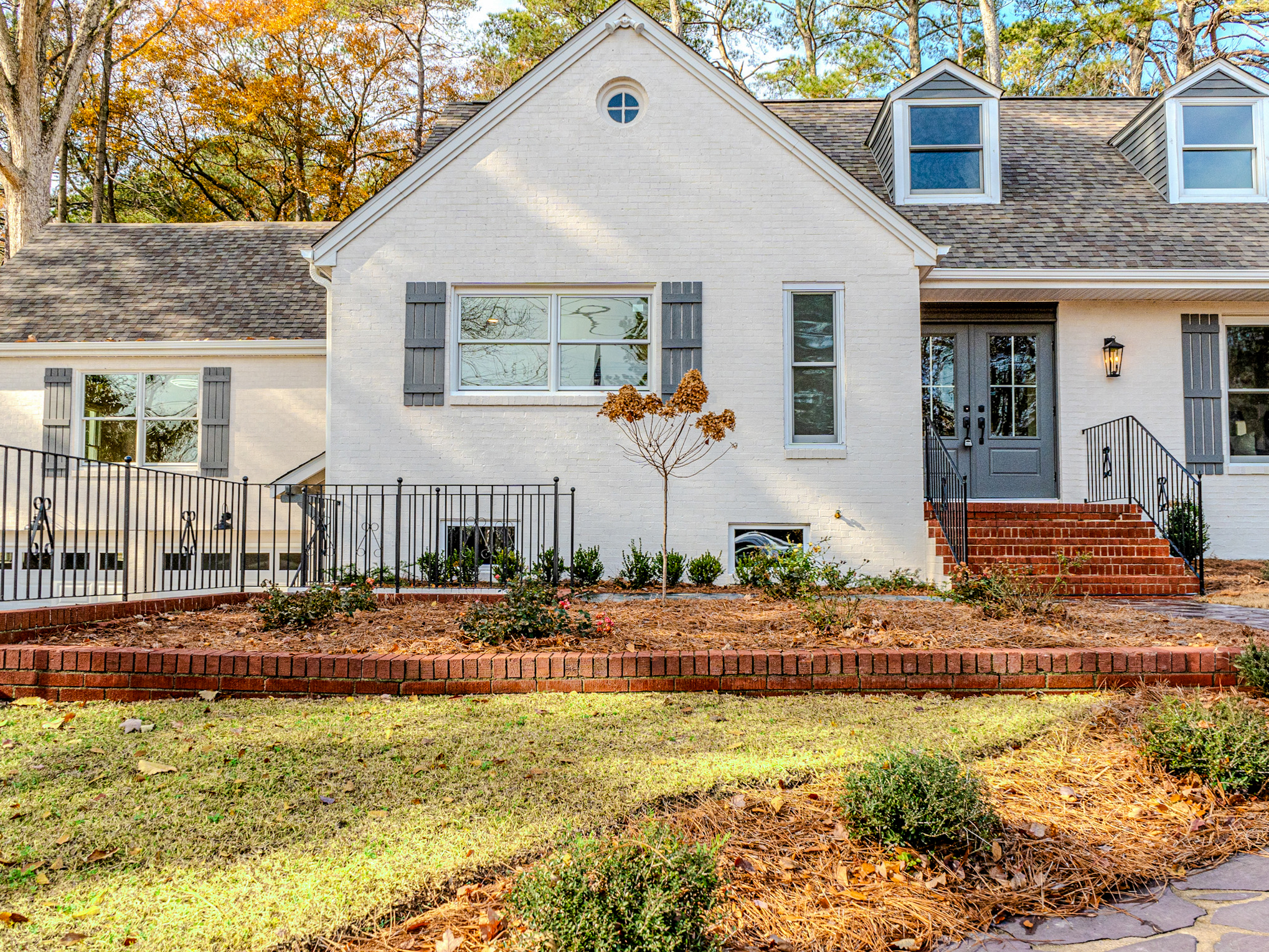 White cottage with iron fence at the front.