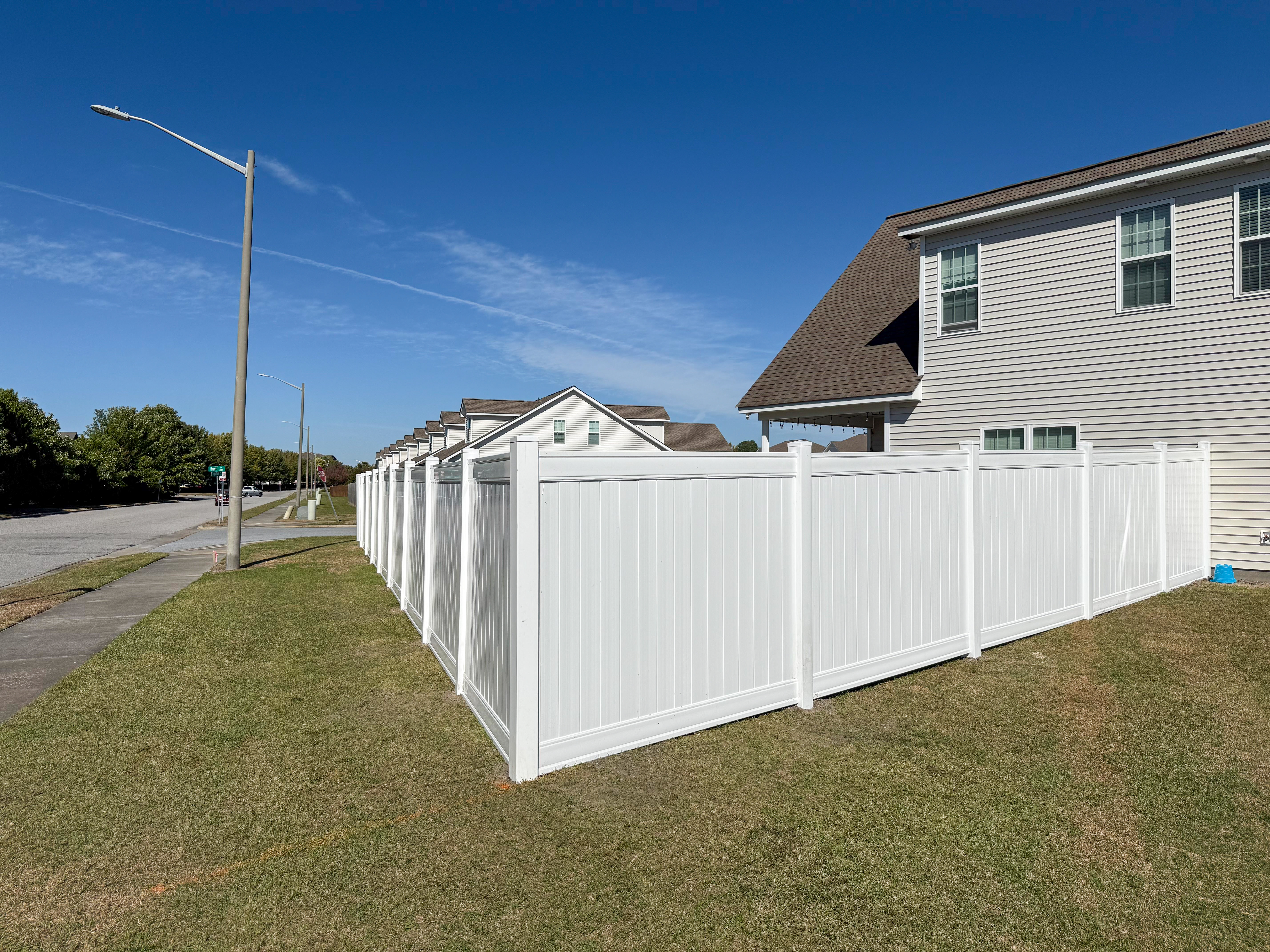 White vinyl fence at a residential corner.