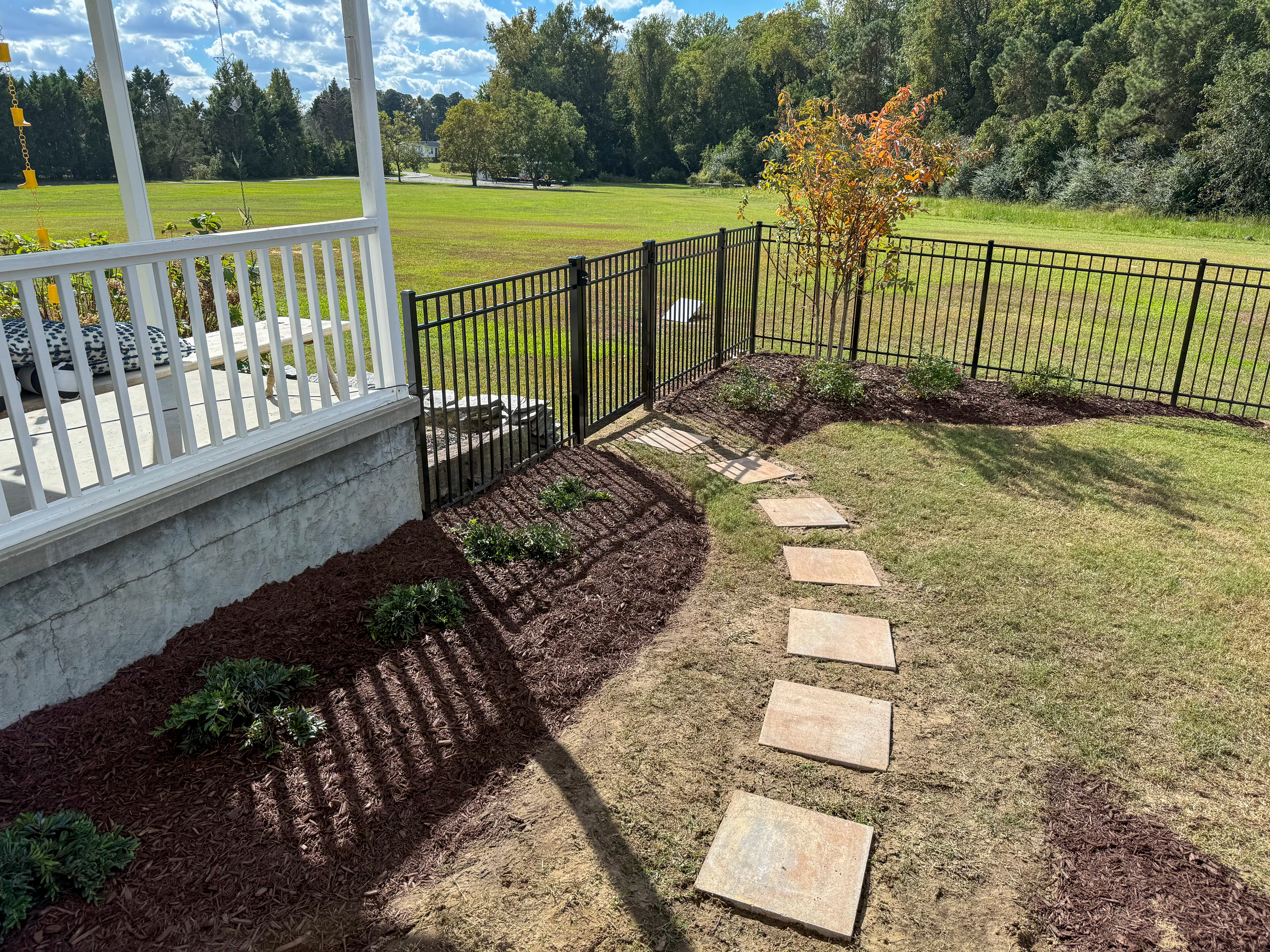 Flagstone stepping stones along an iron fence.