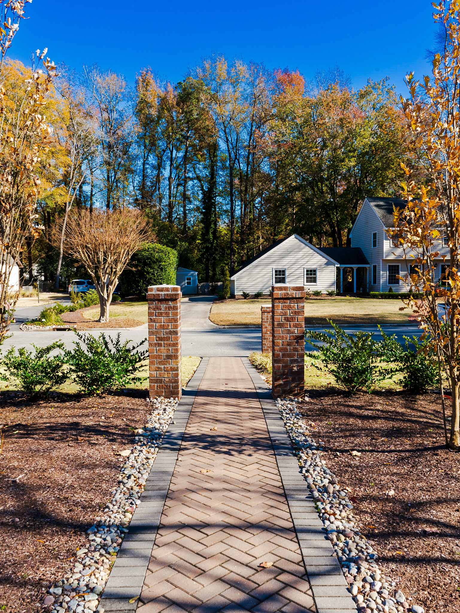 Herringbone paver walkway threaded between brick pillars.