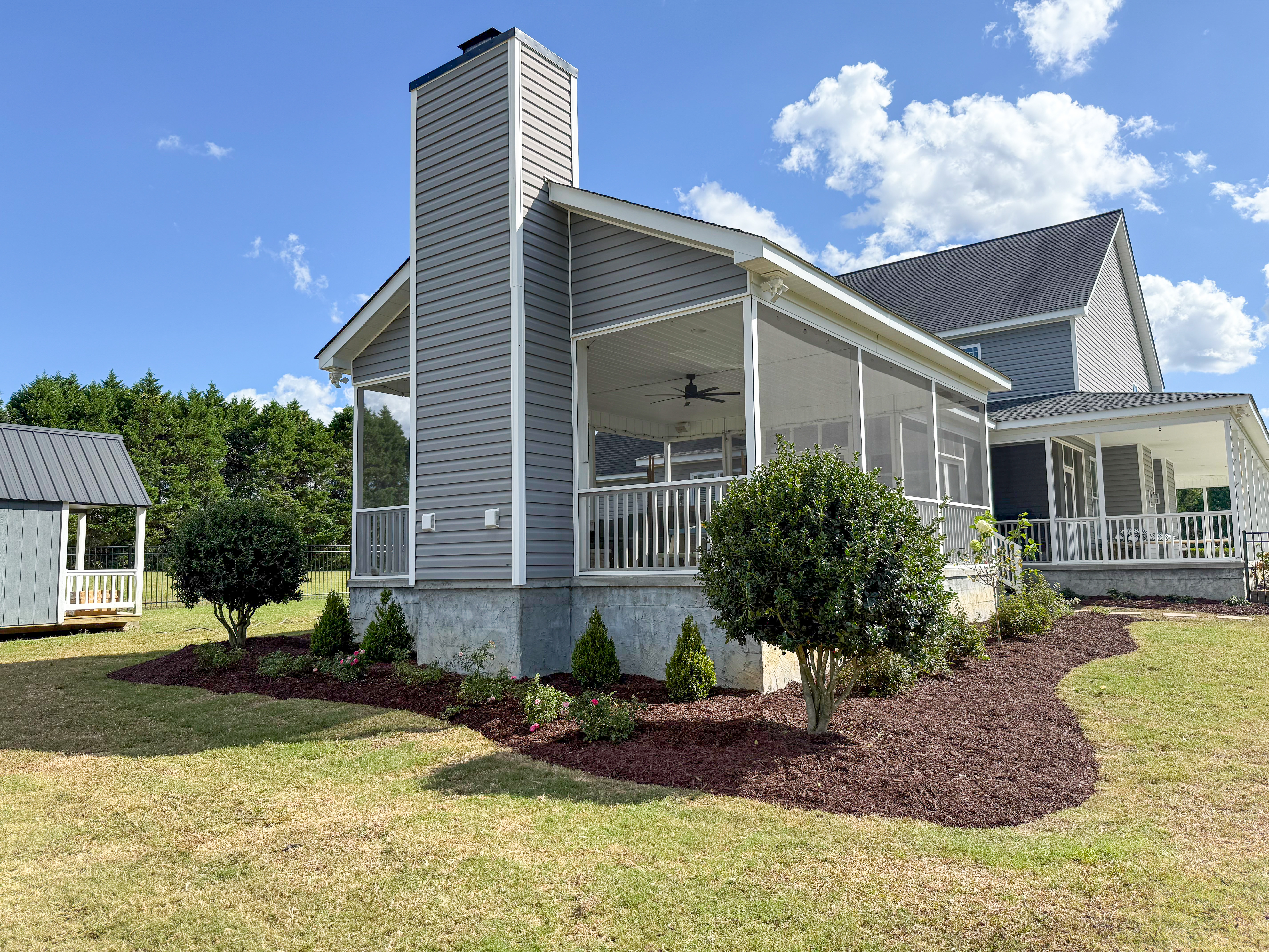 Side foundation bed with fresh mulch and healthy shrubs.