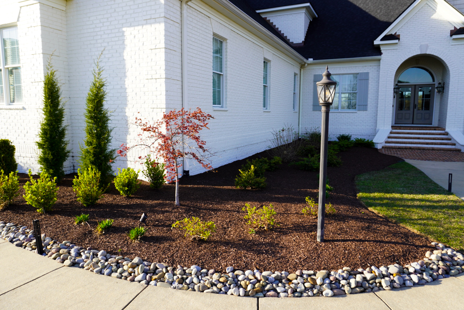 Front foundation bed with river-rock edge.