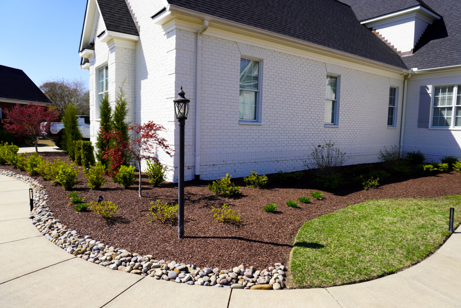 Side foundation bed with river-rock edge.