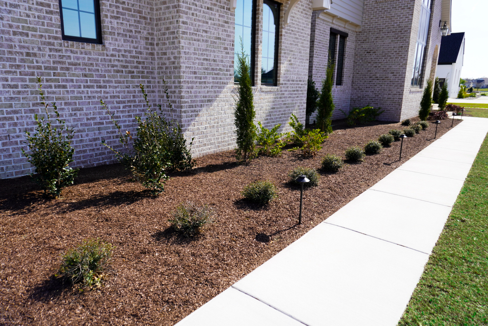 Tan-brick home — side foundation bed.