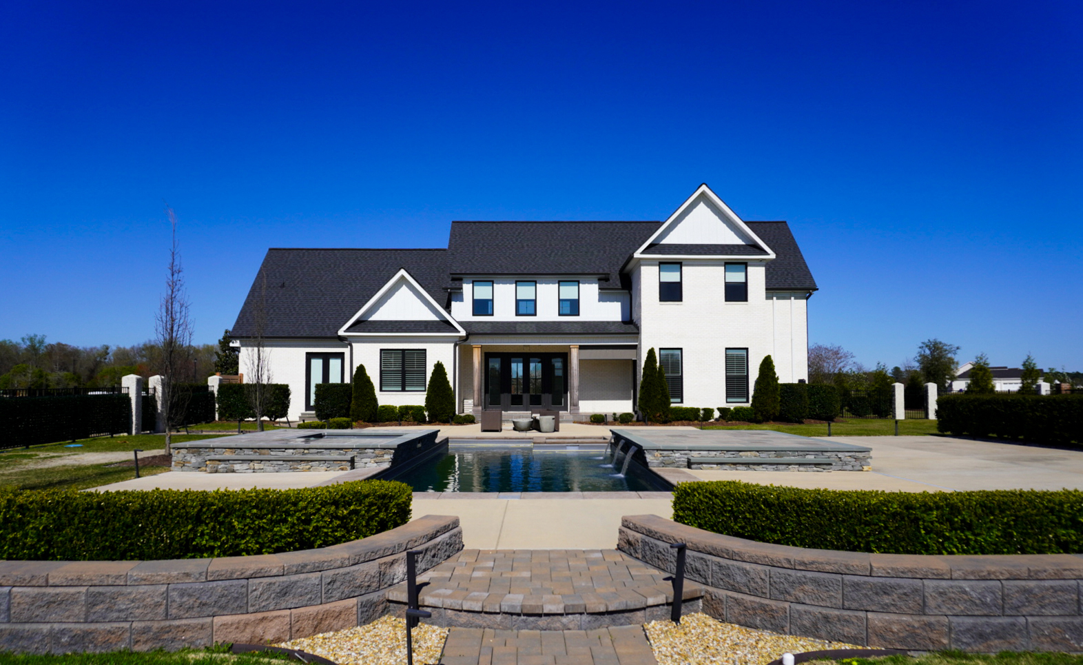 White-brick side elevation with formal hedge foundation bed.