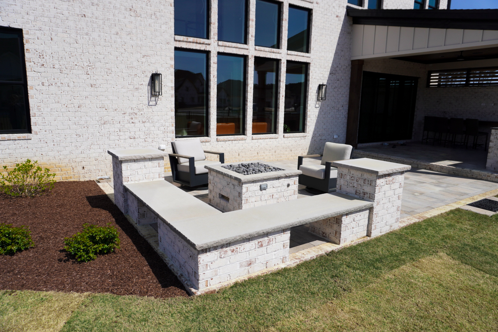 Brick firepit with corner bench on a rear patio.
