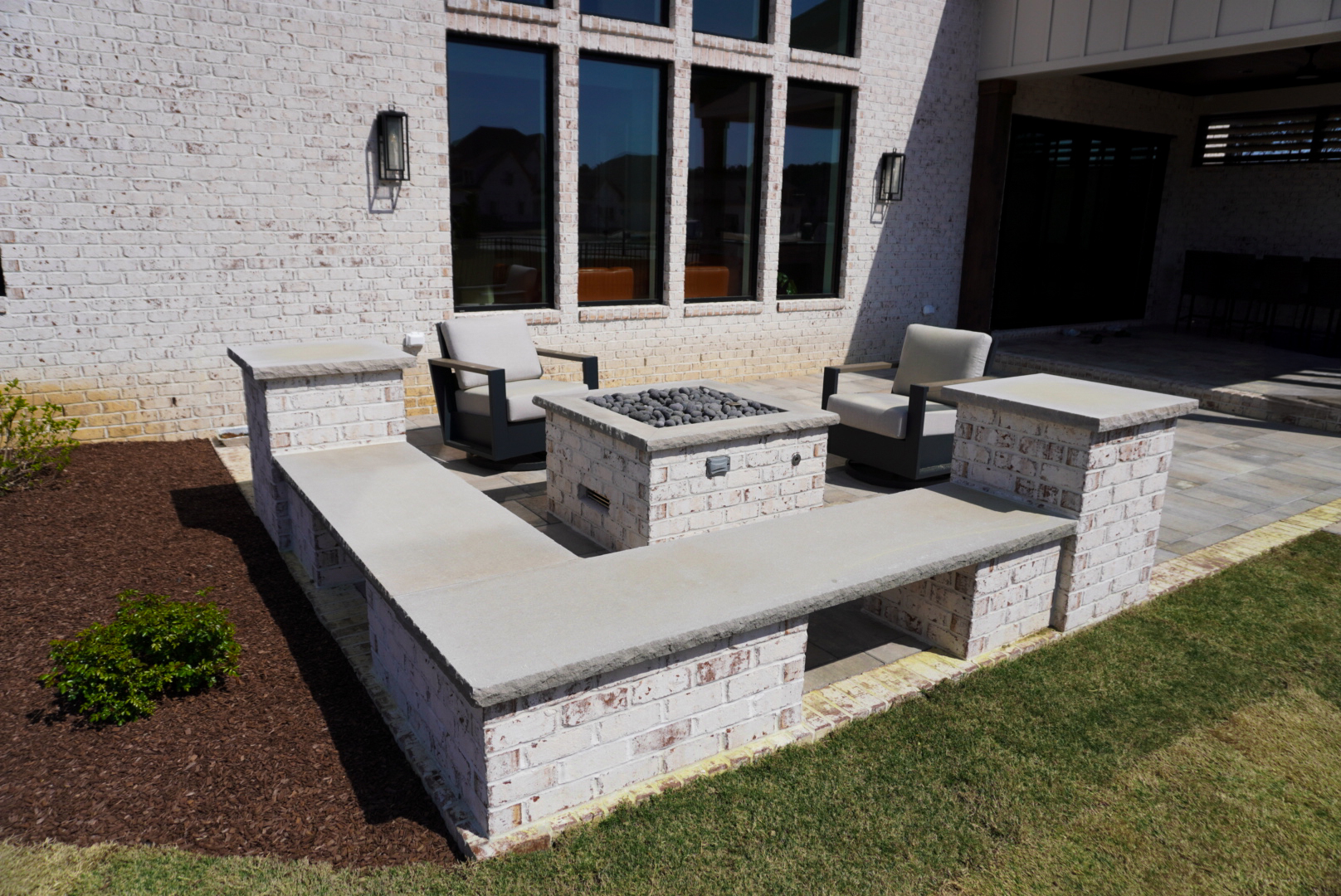 Brick firepit with built-in bench on a rear patio.