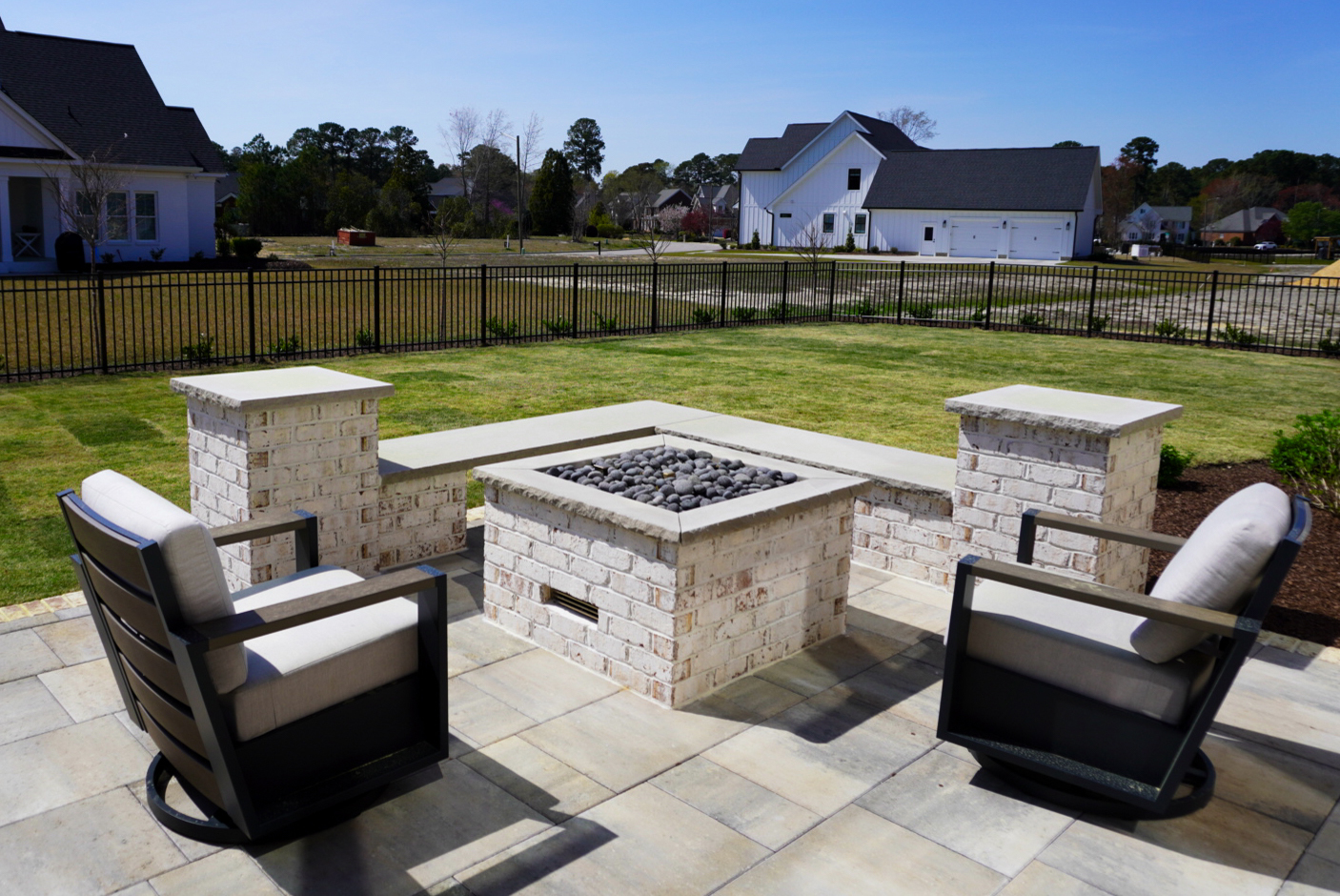Rear-patio firepit beside an iron fence.