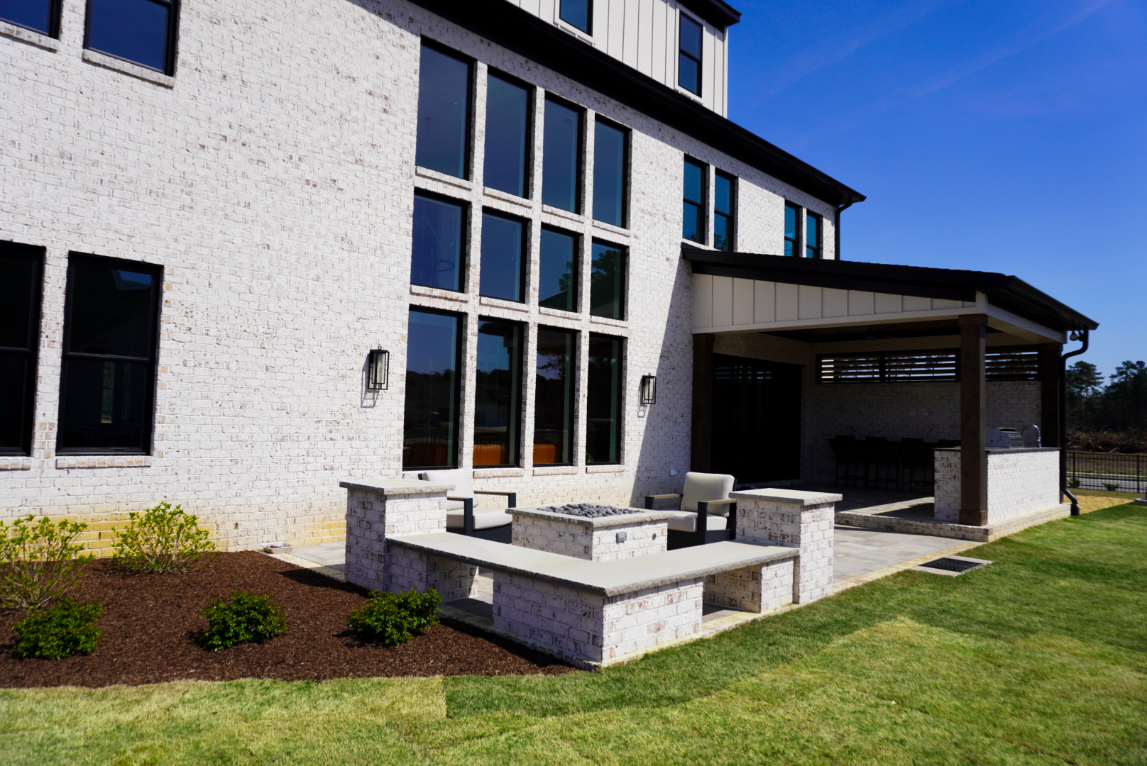 White-brick rear yard with firepit and pergola.