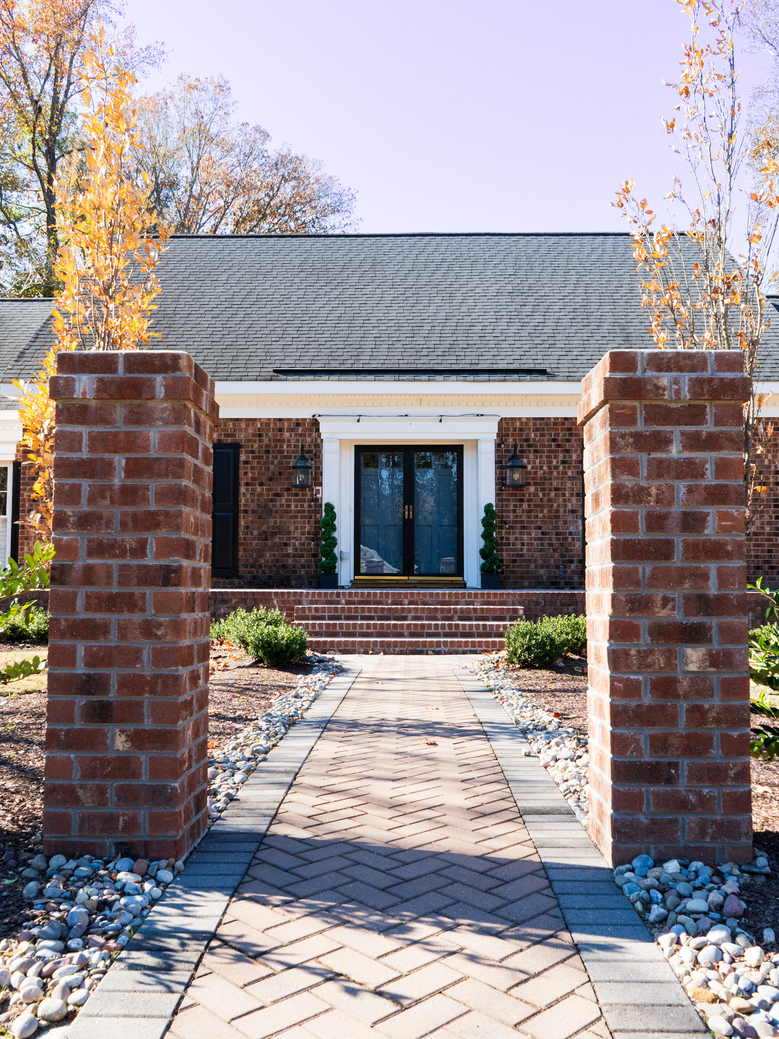 Lighted brick columns at the entry of a residential property.