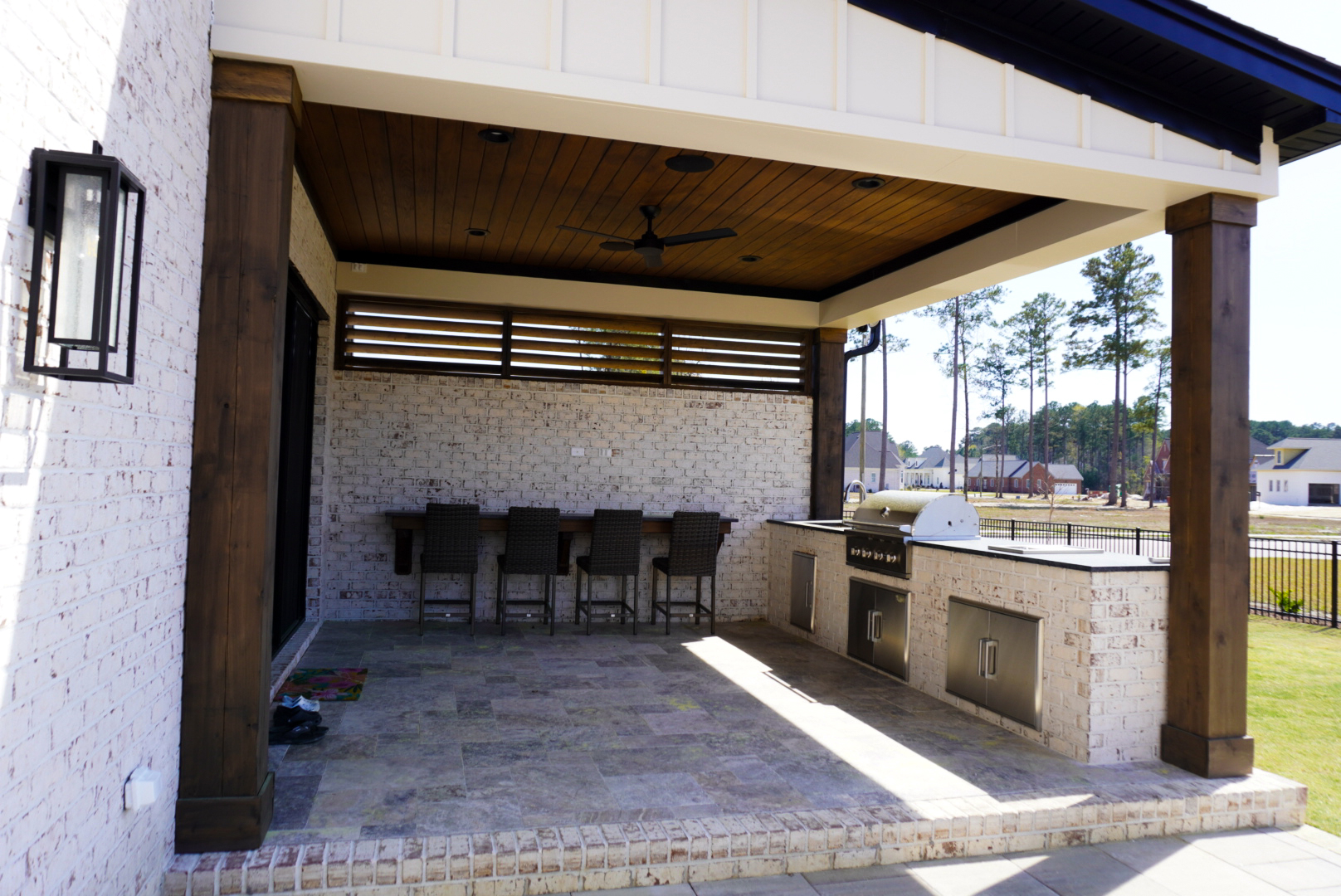 Covered outdoor kitchen with wood columns and integrated counter run.