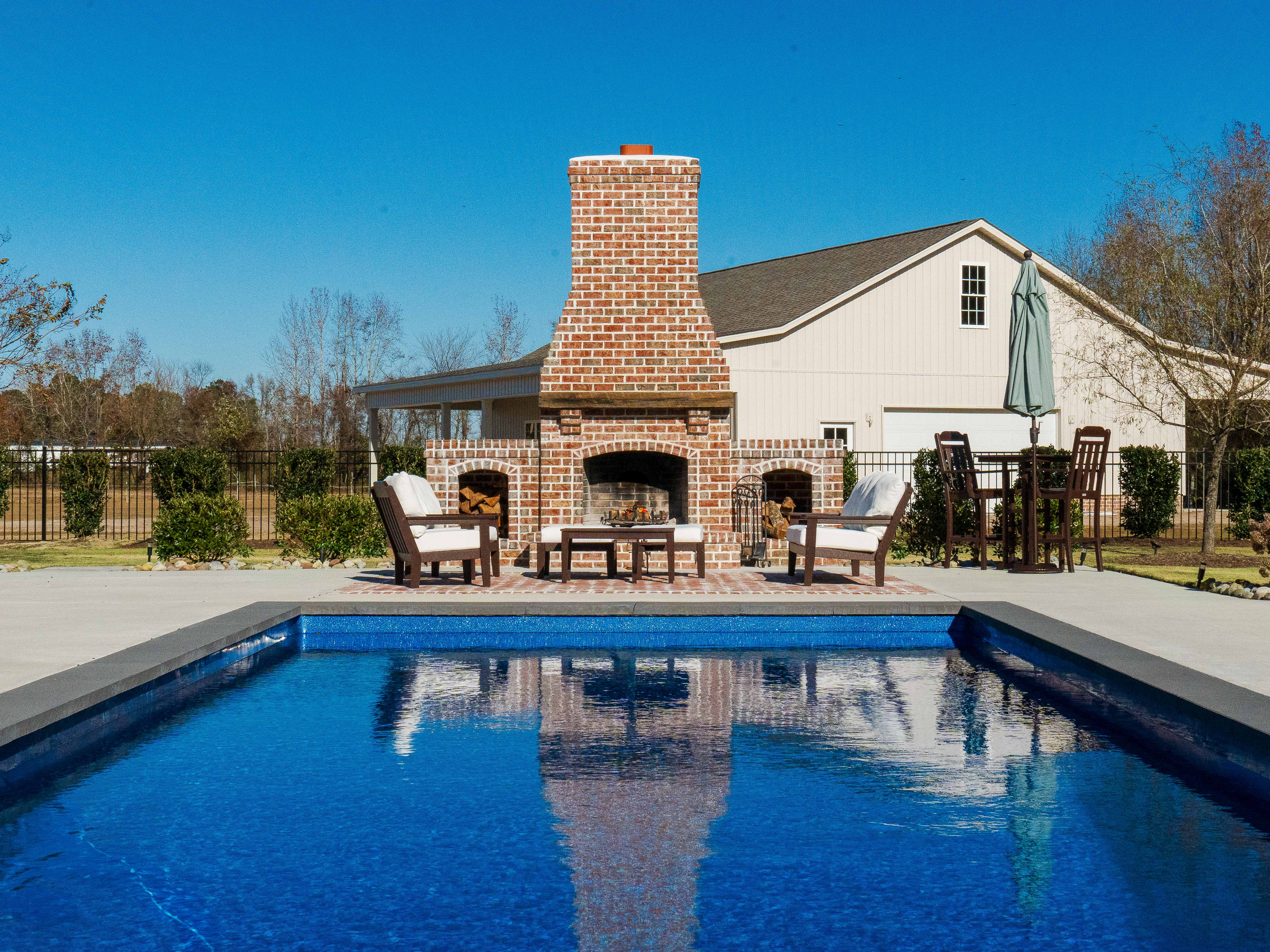 Brick fireplace by pool at twilight.