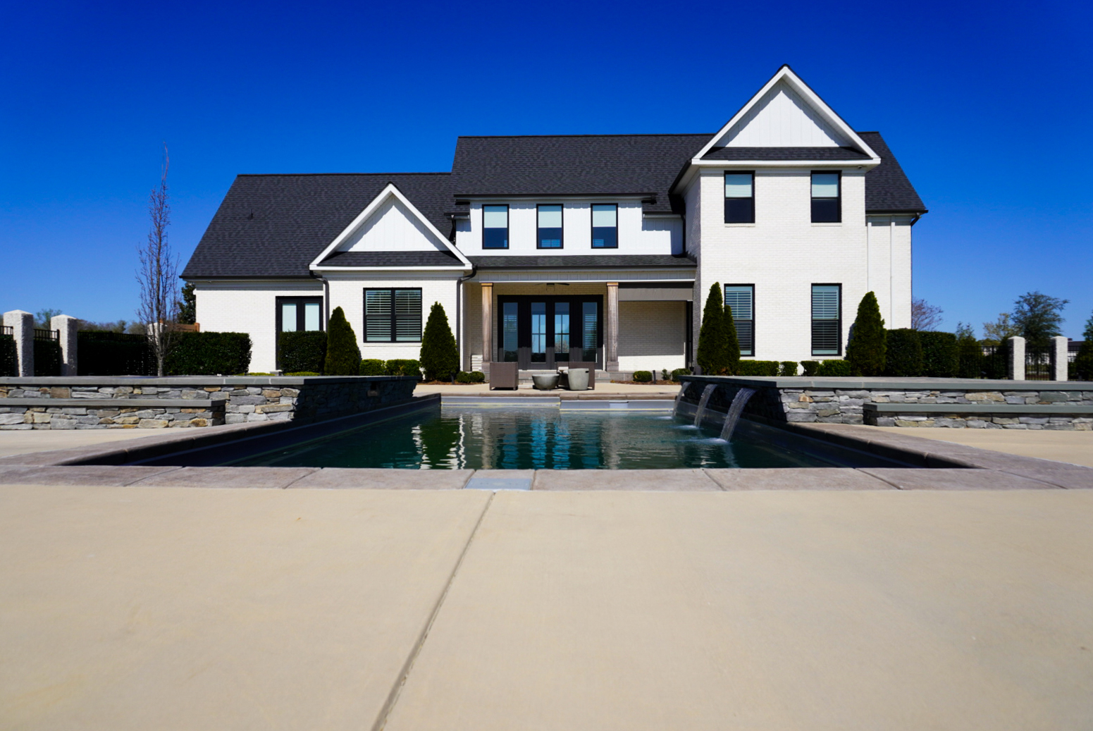 Modern farmhouse front elevation with symmetric pool.