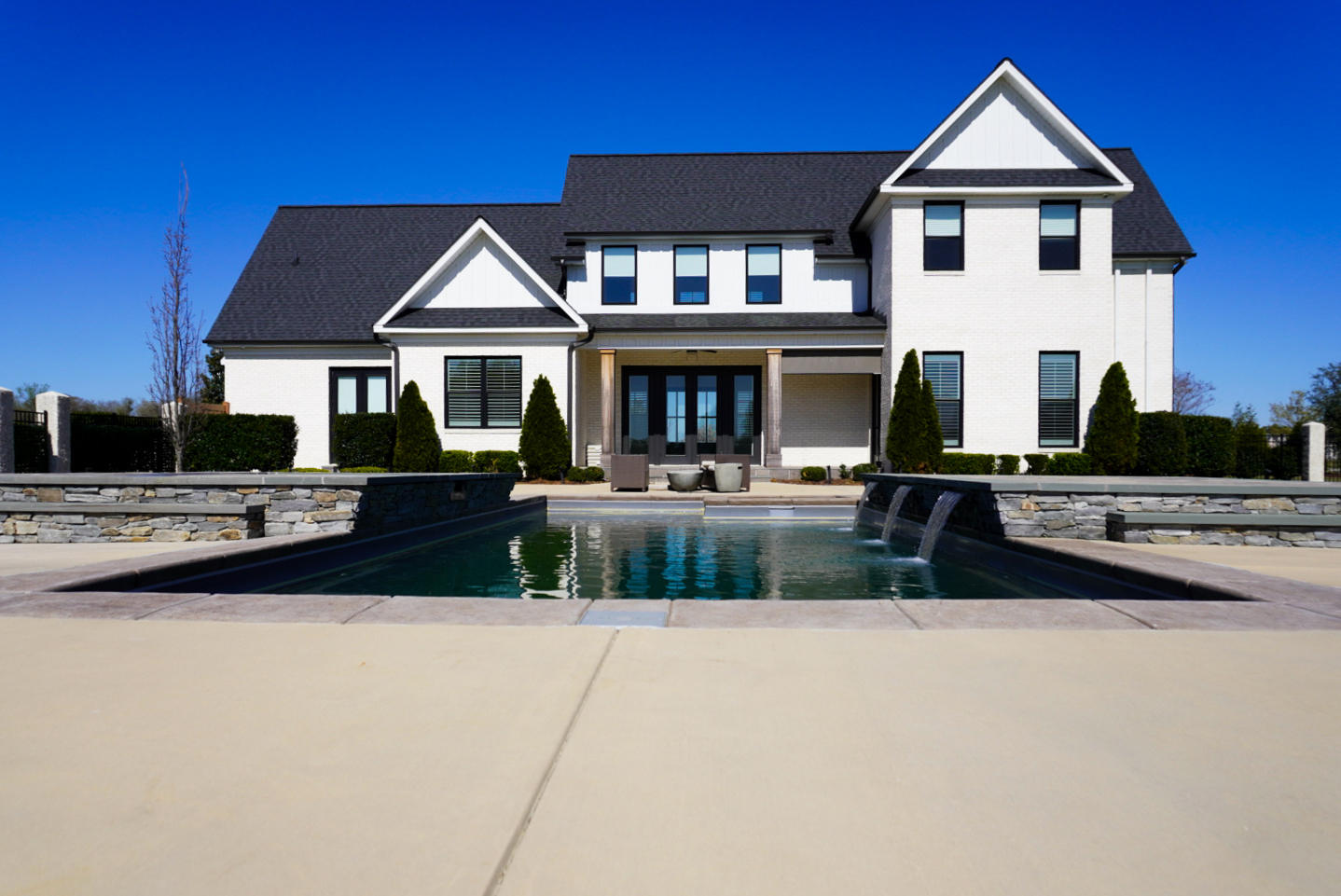 Modern farmhouse rear with pool and paver walk.