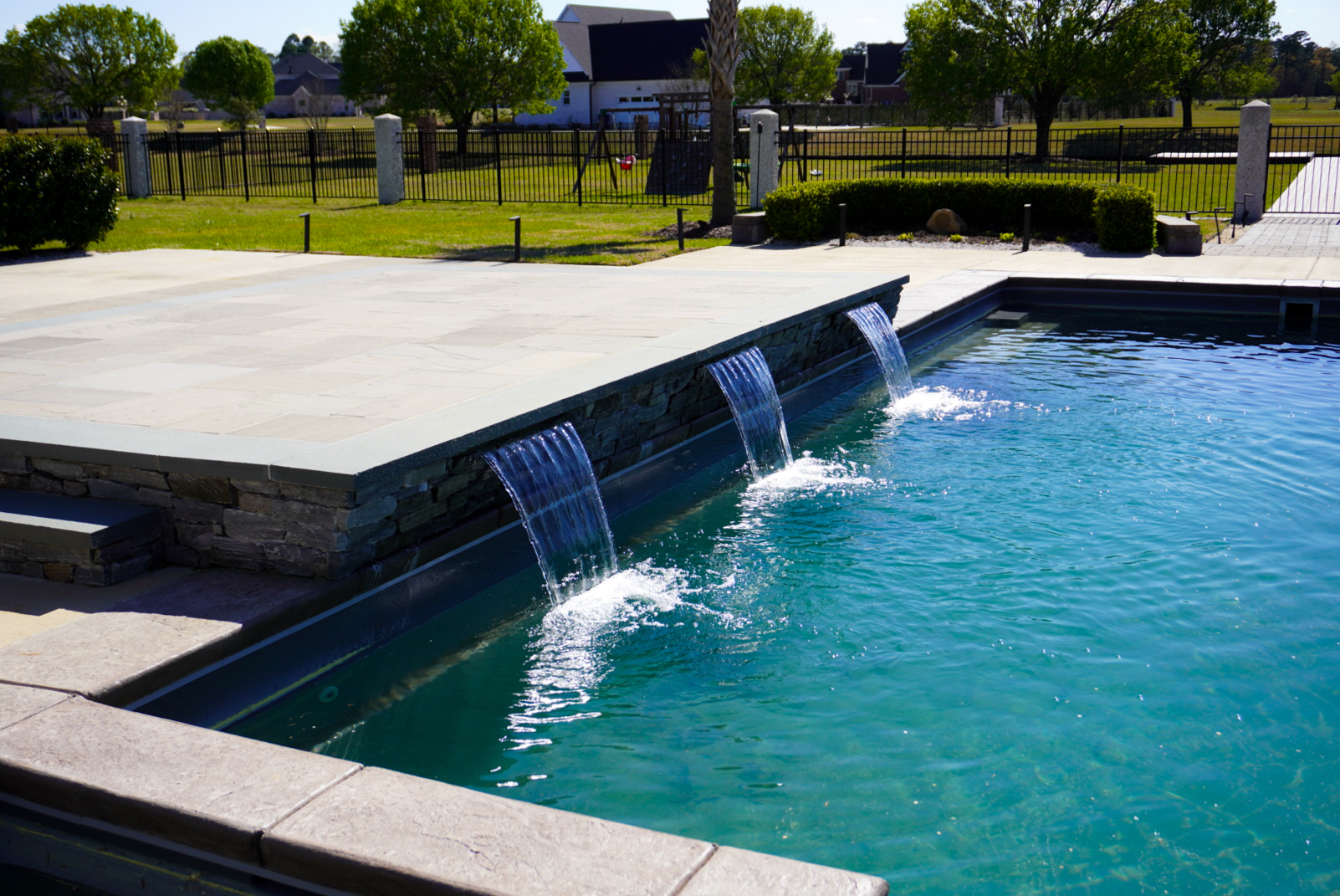 Modern pool with stone-veneer spillway.