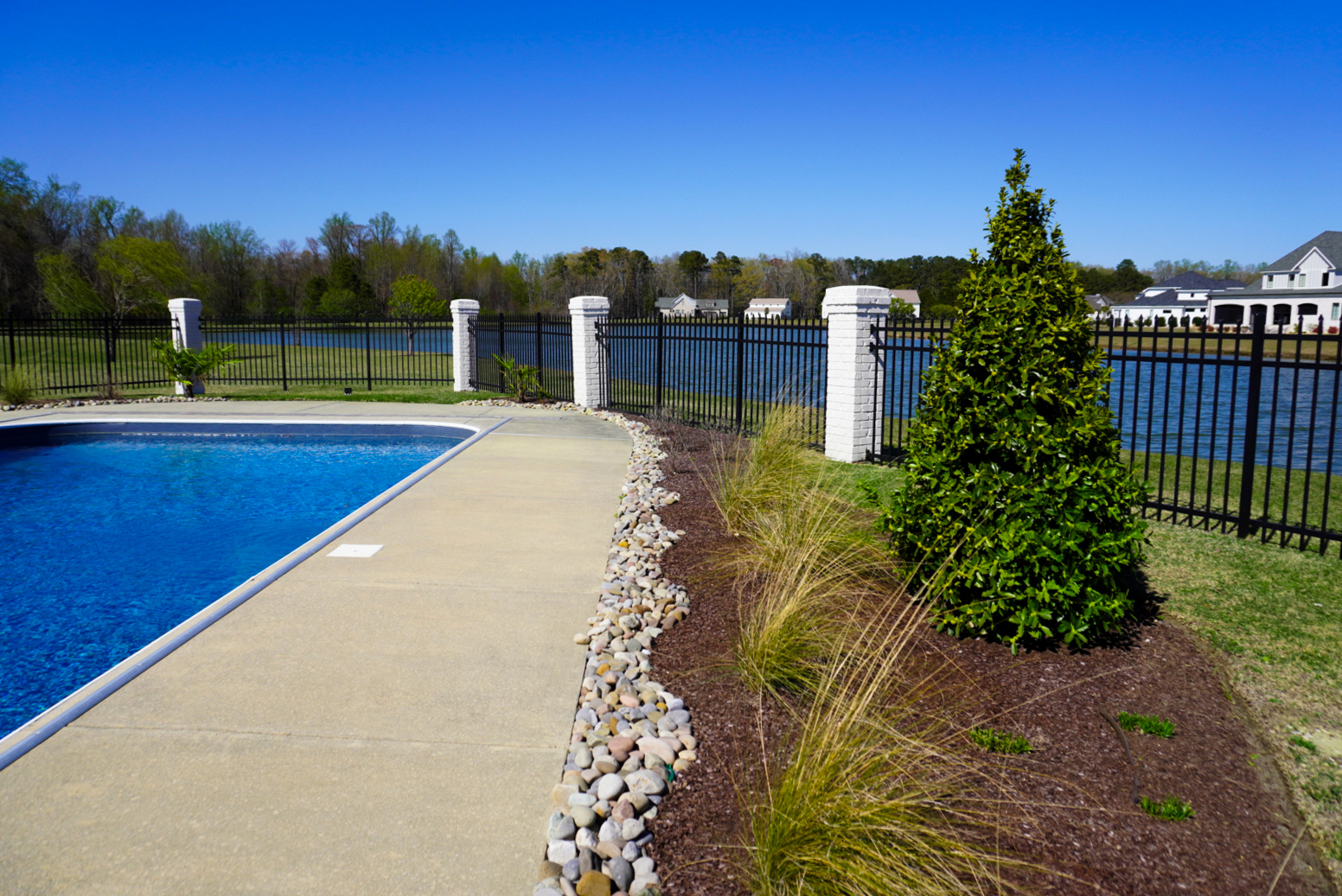Pool deck with arborvitae and pond view.