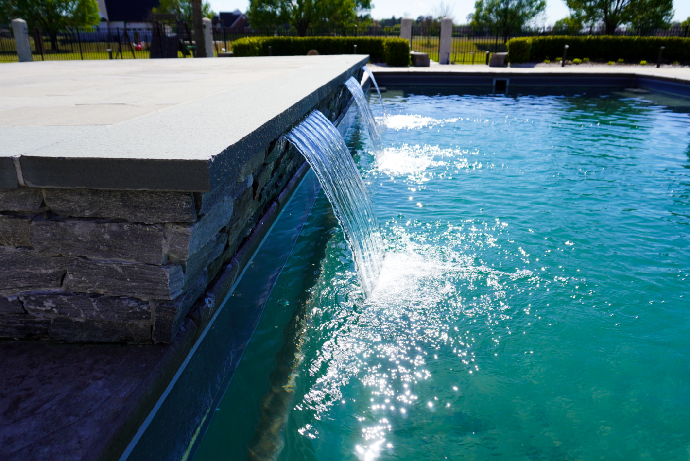 Pool with three stone spillways and deck.