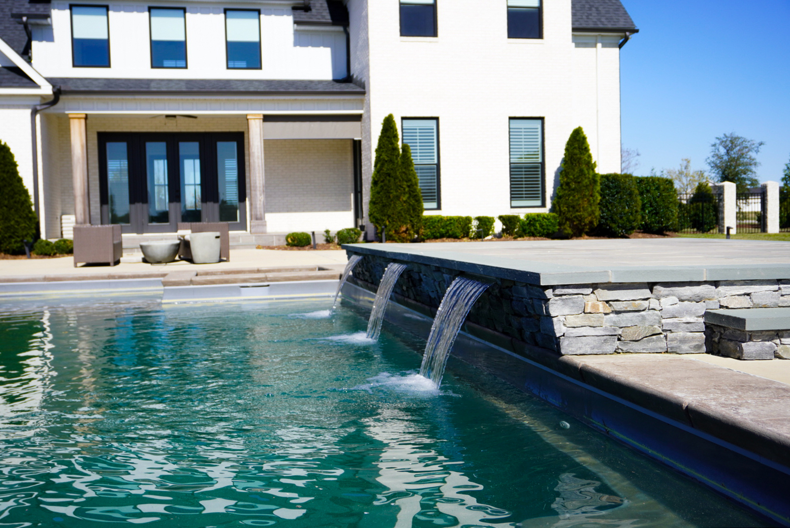 Pool with twin spillways and house backdrop.