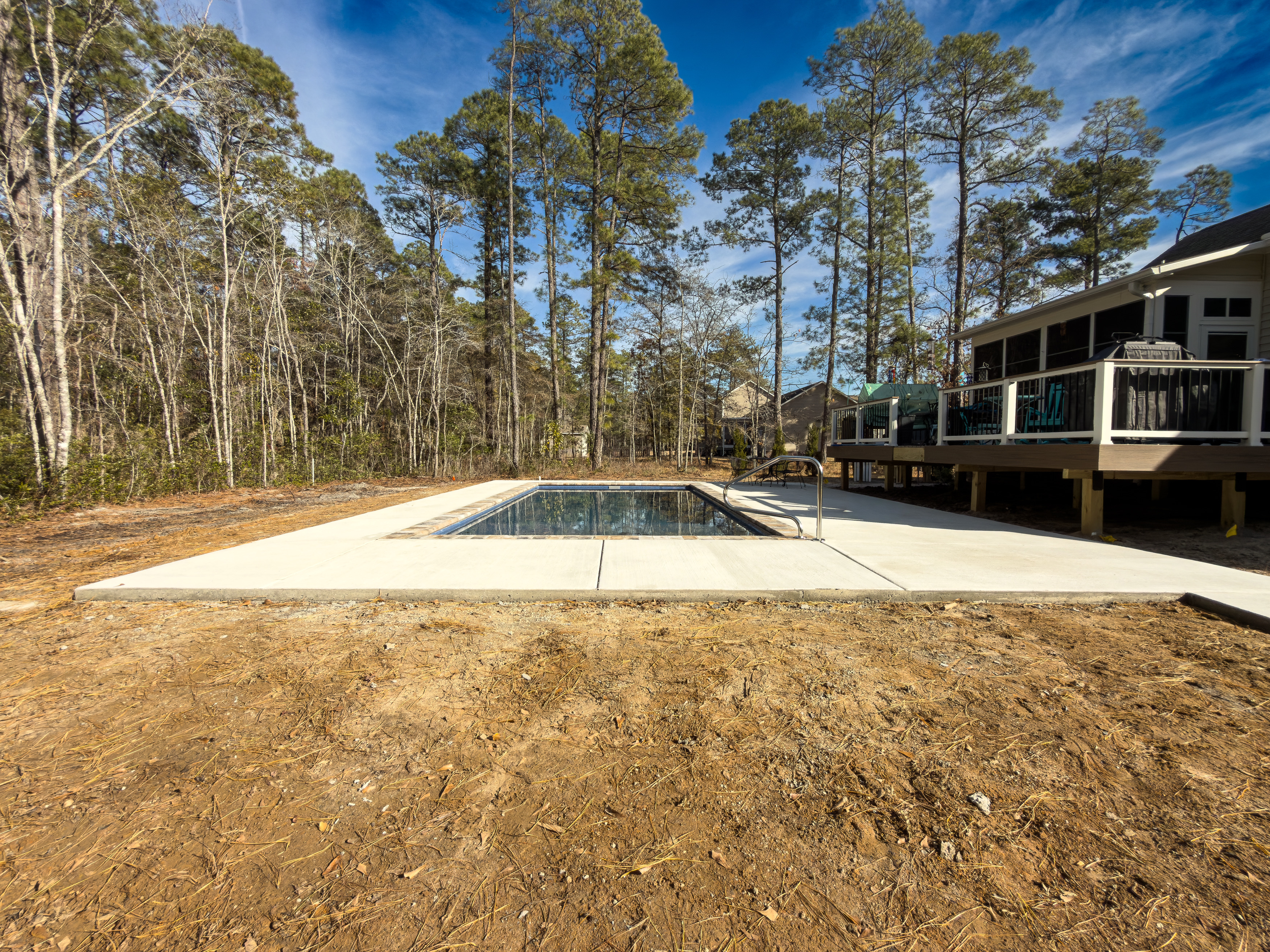 Rectangular pool deck adjacent to a screened porch.