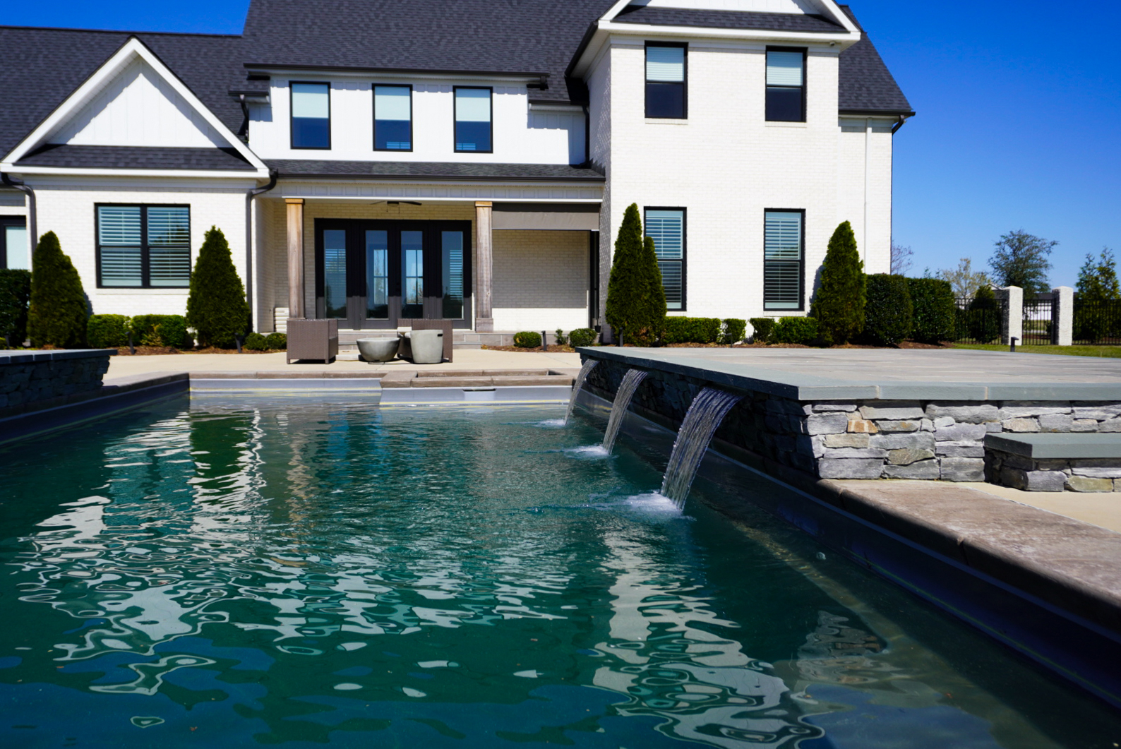 White farmhouse pool with stone spillway.
