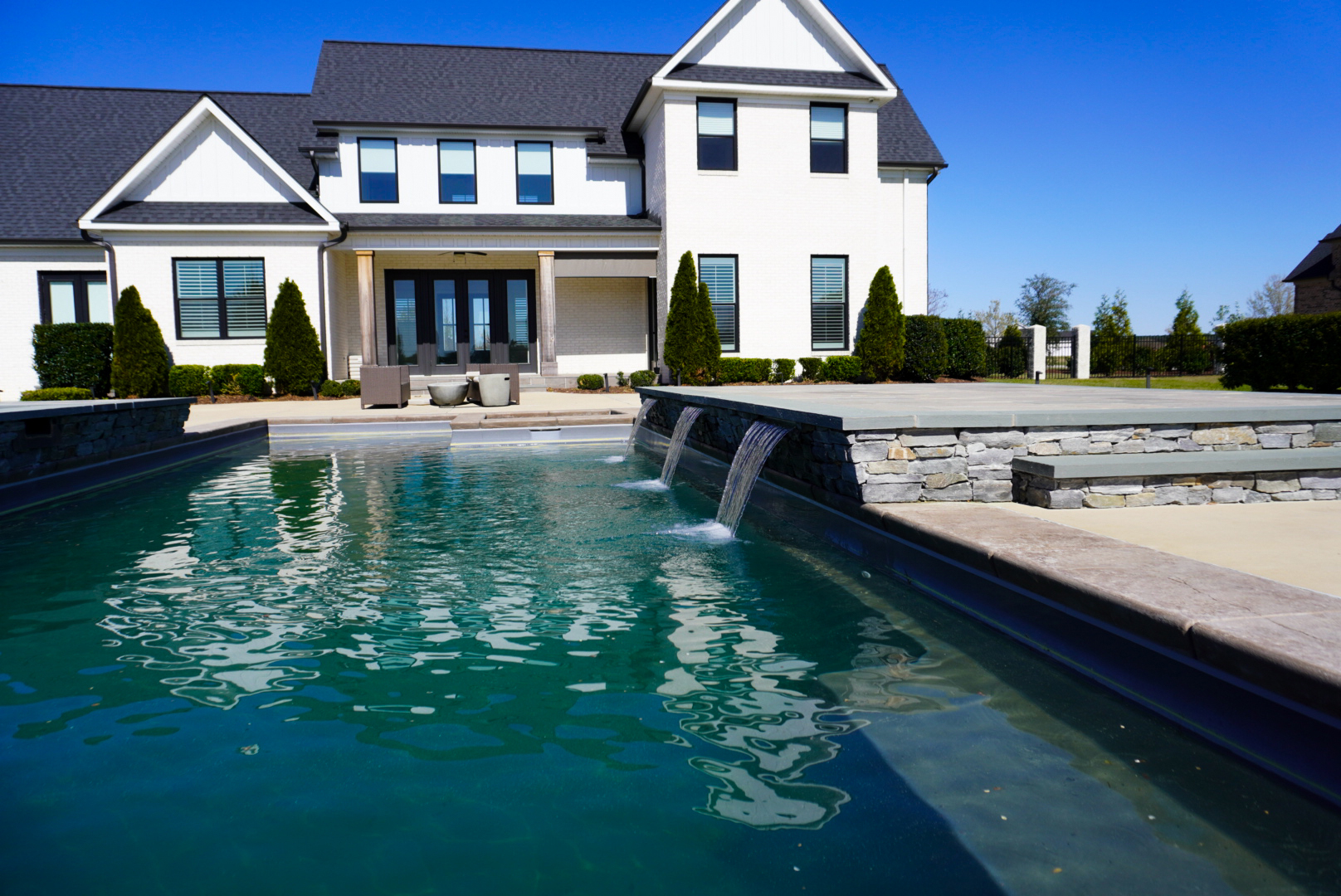 White farmhouse front with pool and spillway.